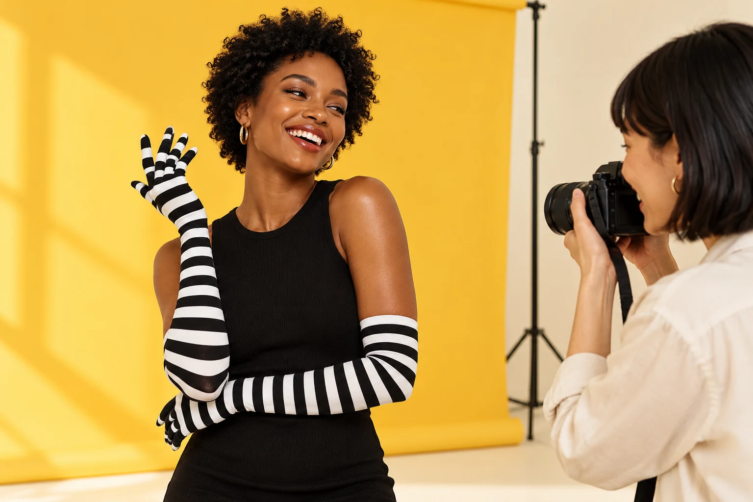 A creator in long striped gloves posing for a photographer against a yellow backdrop